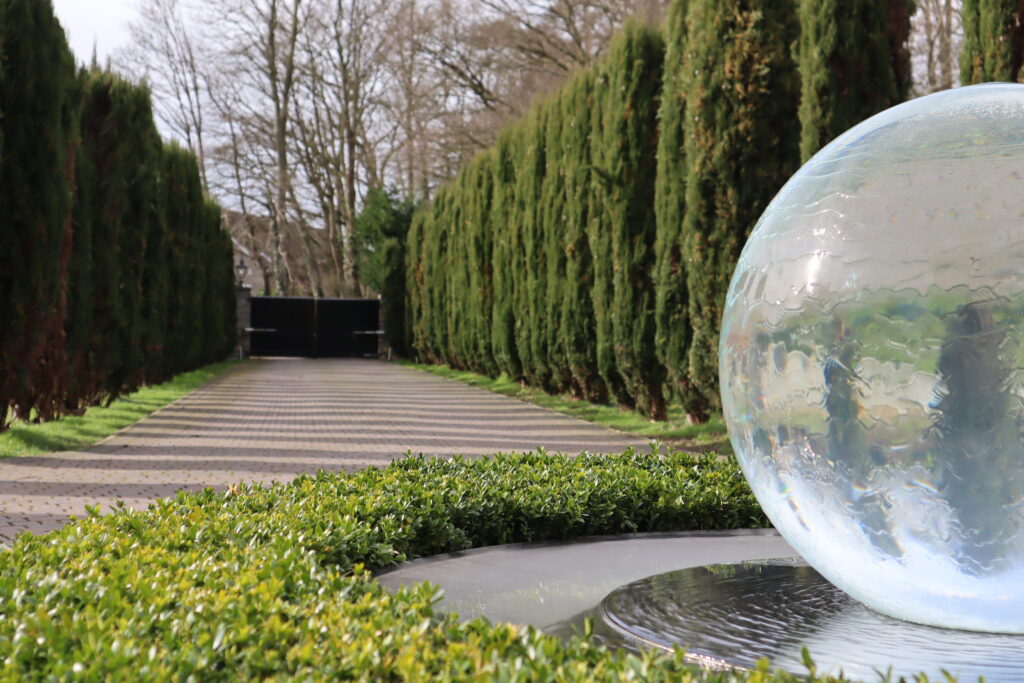 Clipped yew avenue with a glass water feature in the school grounds